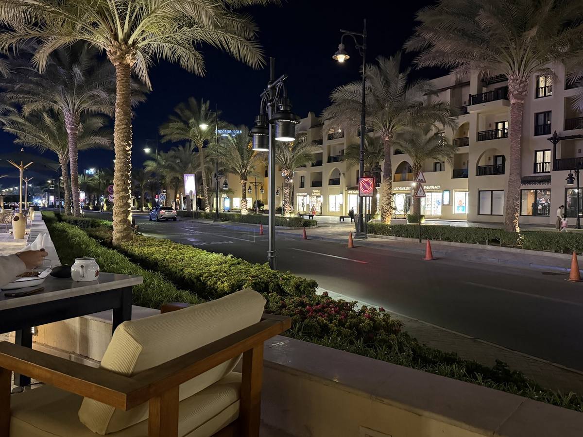 Beleuchtete Straße mit Palmen und Restaurantterrasse an der Aldau-Promenade in Hurghada am Abend