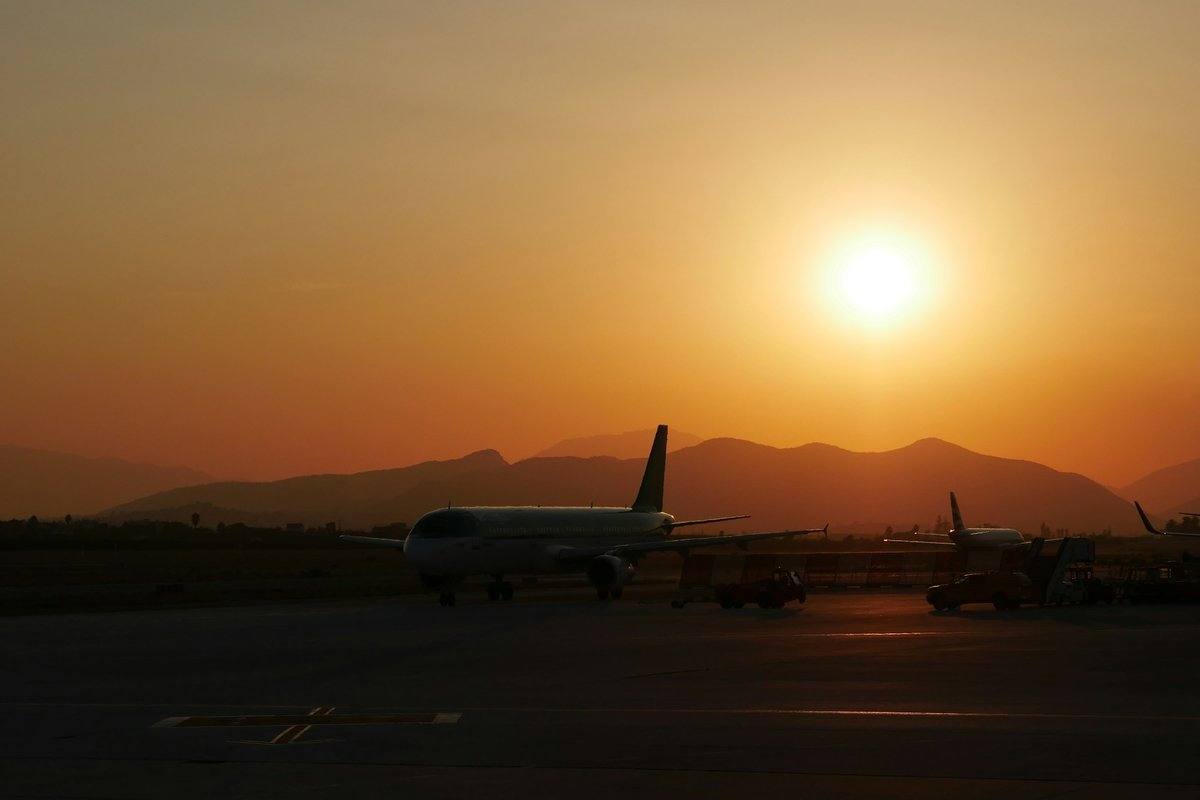 Flugzeug auf dem Vorfeld des Flughafens Hurghada bei Sonnenuntergang, dahinter Berge als dunkle Silhouette