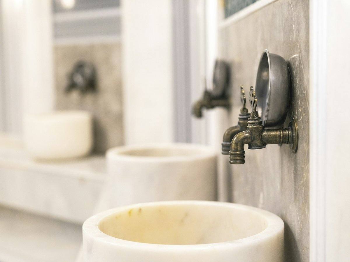 Marmorbecken mit Messinghähnen und Wasserschale an der Wand eines traditionellen türkischen Bades