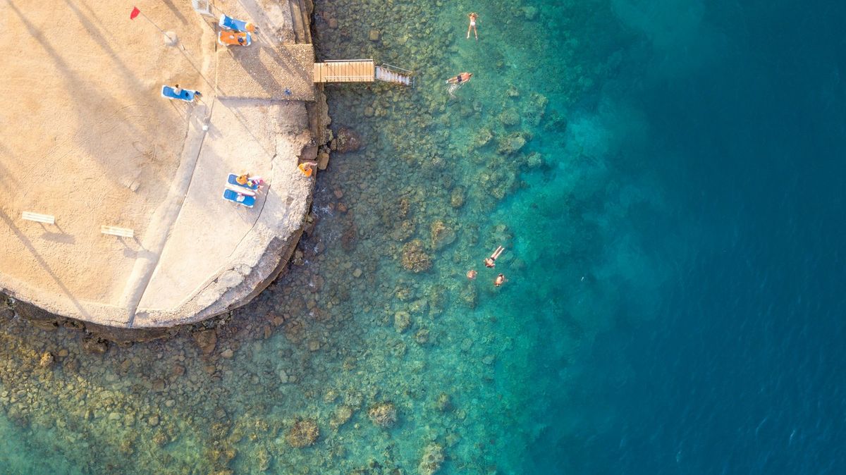 Luftaufnahme von Strand und Riff, Schwimmer im klaren Wasser