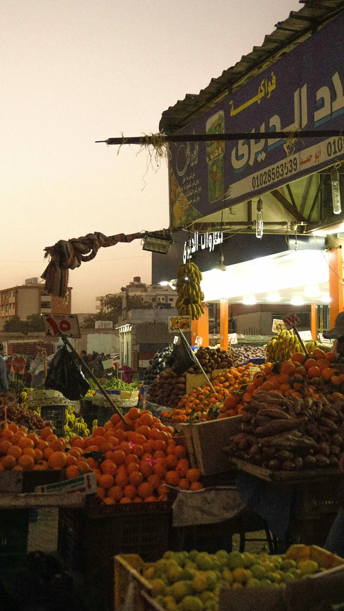 Marktstand mit Orangen, Tomaten und anderem Obst und Gemüse in der Abendsonne