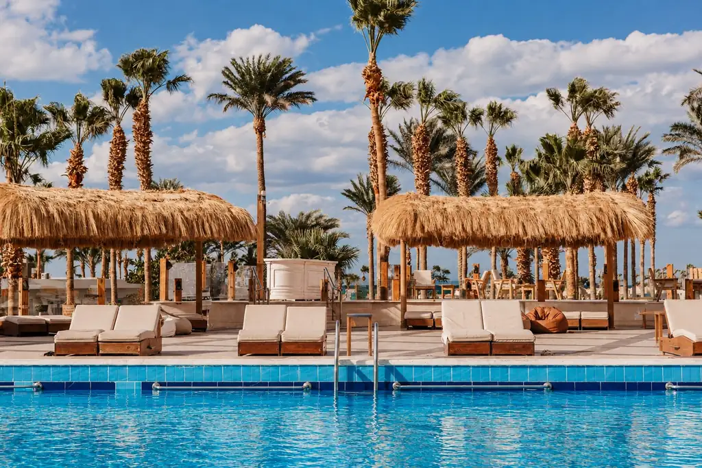 KI-Illustration: Pool mit Stroh-Cabanas im Meraki Resort