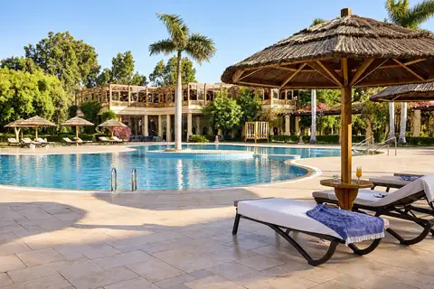 KI-Illustration: Hauptpool mit Liegeterrasse und Strohdachschirmen im Robinson Soma Bay