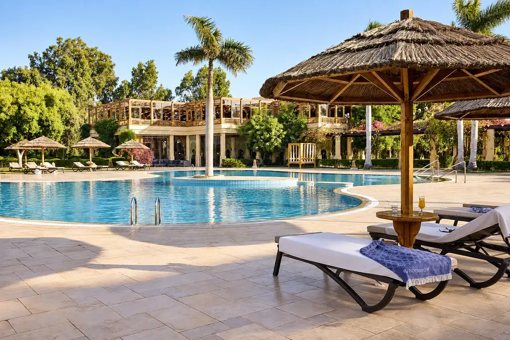 KI-Illustration: Hauptpool mit Liegeterrasse und Strohdachschirmen im Robinson Soma Bay