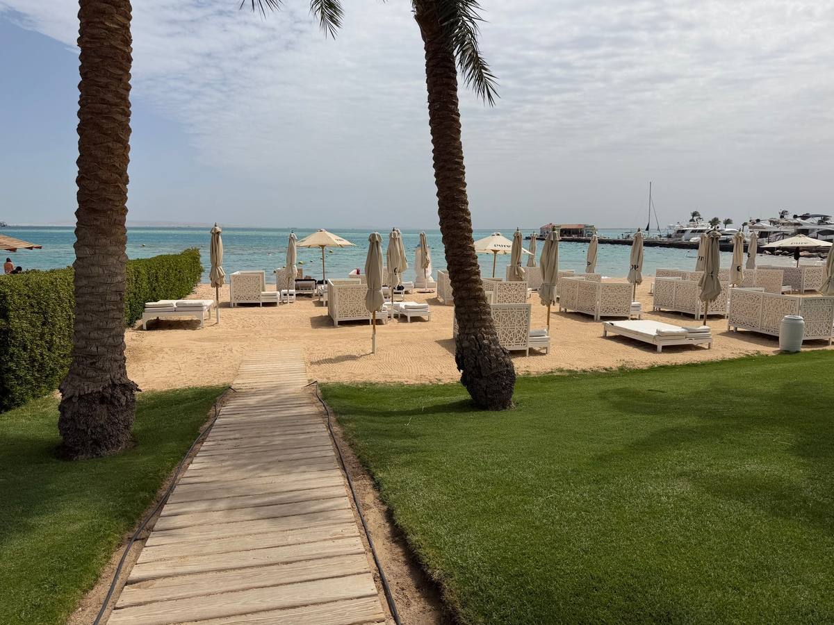 Holzweg über den Rasen zum Strand mit weißen Liegen im Steigenberger Pure Lifestyle in Hurghada
