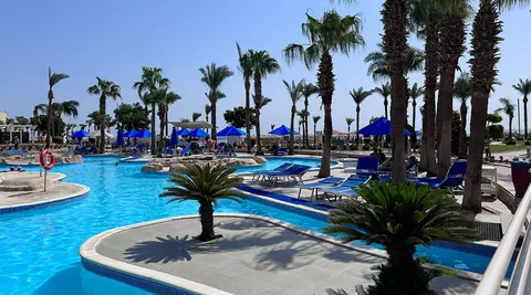 Geschwungene Poollandschaft mit Palmen und blauen Sonnenschirmen im Pickalbatros Palace Resort