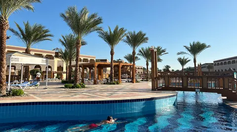 Pool mit Holzbrücke, Palmen und Pavillons im Mamlouk Palace Resort in Hurghada